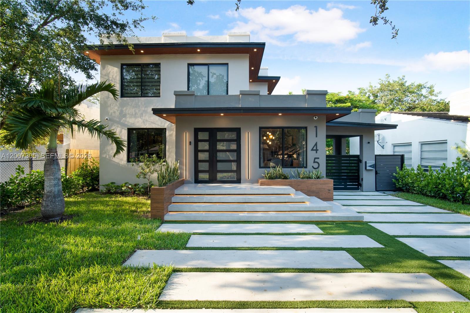 A modern two-story house features a concrete driveway, illuminated steps, and a flat roof — 145 NE 49th St # A, Miami FL 33137, MIAMI, FL