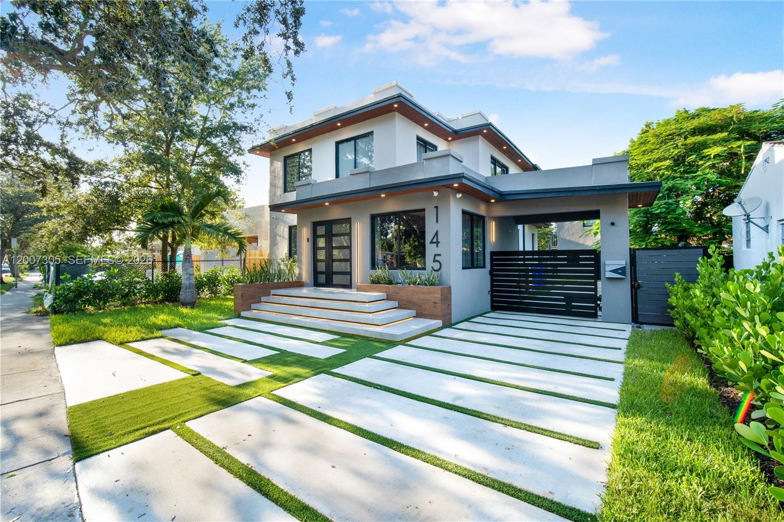 A modern two-story house features a concrete driveway, floating steps, and a black gate — 145 NE 49th St # A, Miami FL 33137, MIAMI, FL