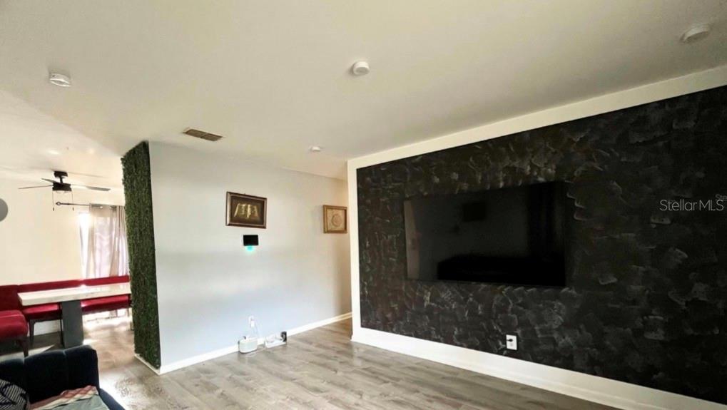 A living room features a dark textured accent wall with a mounted television — 7011 CONIFER DRIVE, TAMPA, FL