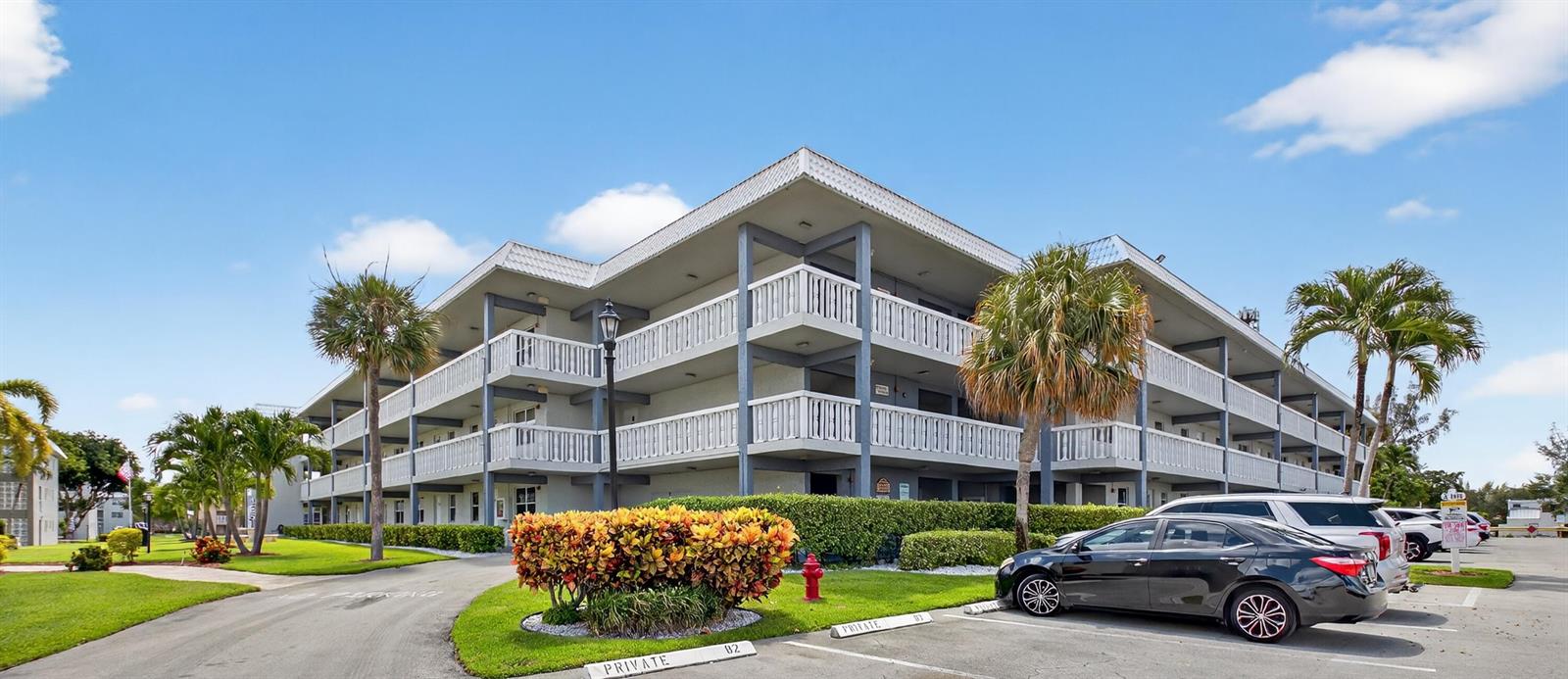 A multi-story apartment building with exterior walkways, balconies, and a parking lot in front — 9880 Marina Boulevard # 1509, Boca Raton FL 33428, BOCA RATON, FL