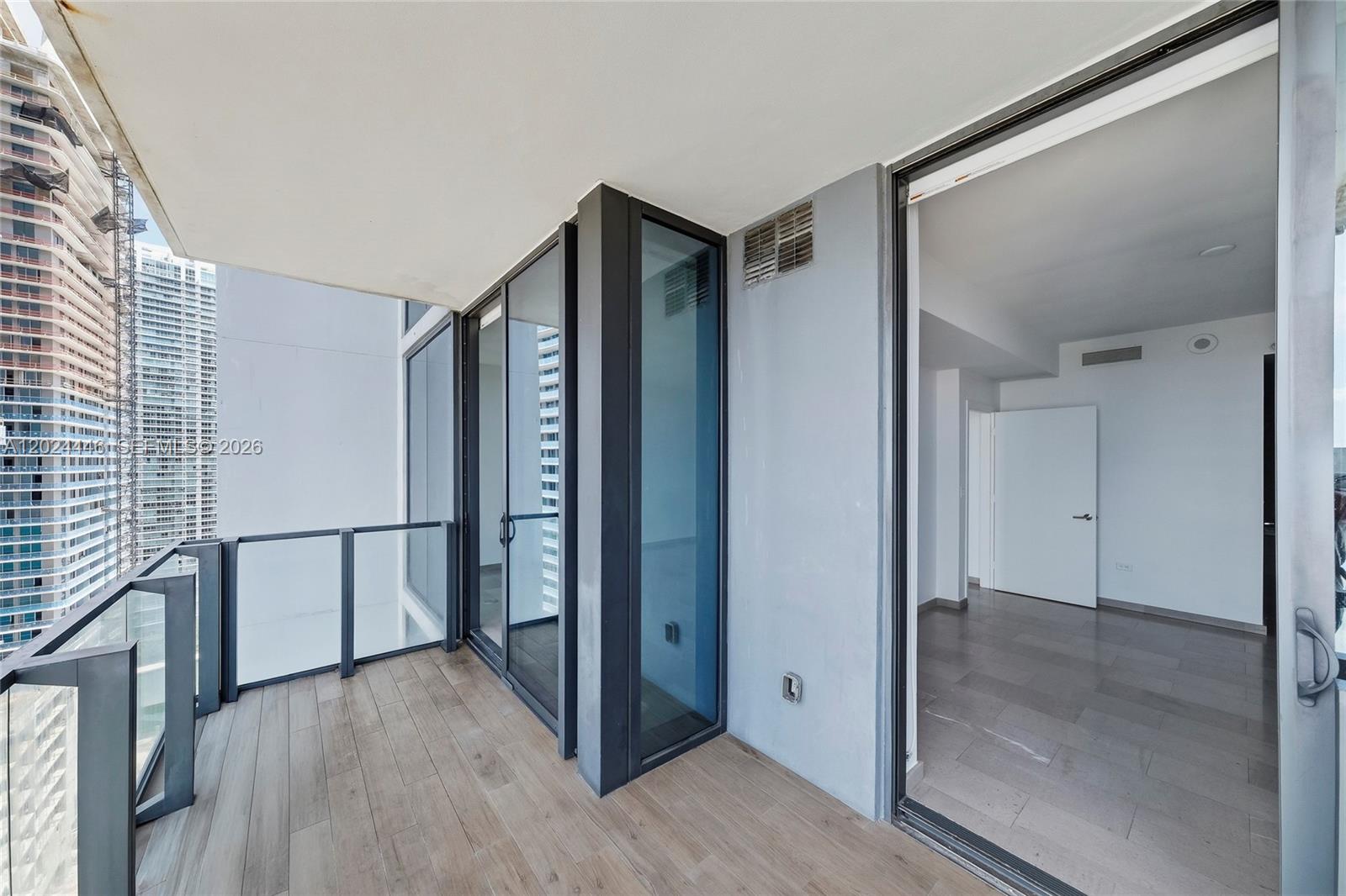 A balcony with wood-look tile flooring overlooks a city skyline with high-rise buildings — 88 SW 7th St # 2008, Miami FL 33130, MIAMI, FL