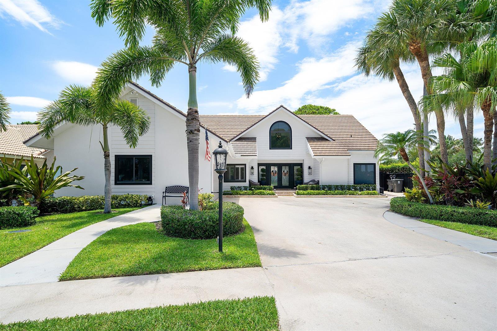 A white house with a brown tile roof, palm trees, and a concrete driveway — 2707 Biarritz Drive, Palm Beach Gardens FL 33410, PALM BEACH GARDENS, FL