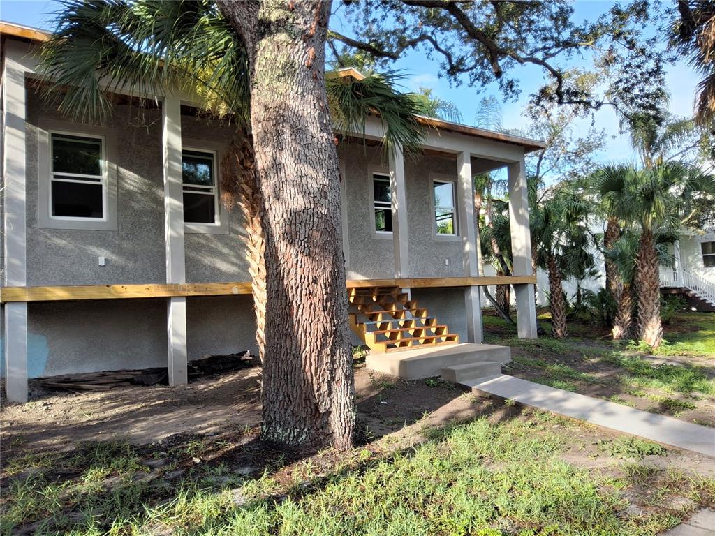 A blue two-story house stands behind several palm trees in a grassy, wooded yard — 383 GEORGIA AVENUE, CRYSTAL BEACH, FL
