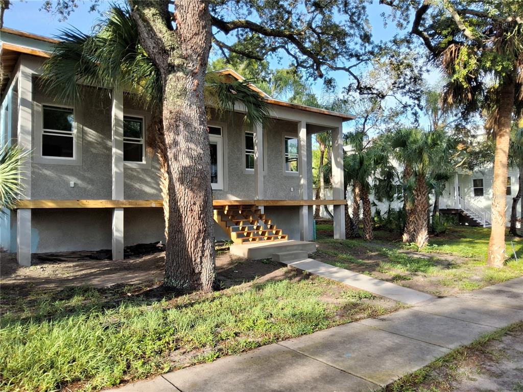 A light blue house with a front porch and wooden stairs stands under large trees — 383 GEORGIA AVENUE, CRYSTAL BEACH, FL