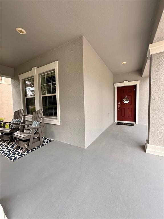 A covered front porch features gray walls, a red door, and two wooden chairs — 14250 BLUE DASHER DRIVE, RIVERVIEW, FL