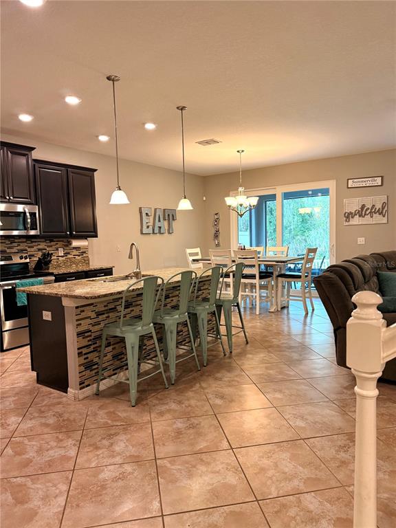 A kitchen with dark cabinets, a granite-topped island, and a dining area with sliding doors — 14250 BLUE DASHER DRIVE, RIVERVIEW, FL