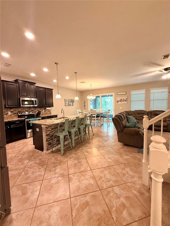 An open-concept kitchen with dark cabinets and a breakfast bar overlooks a living area — 14250 BLUE DASHER DRIVE, RIVERVIEW, FL