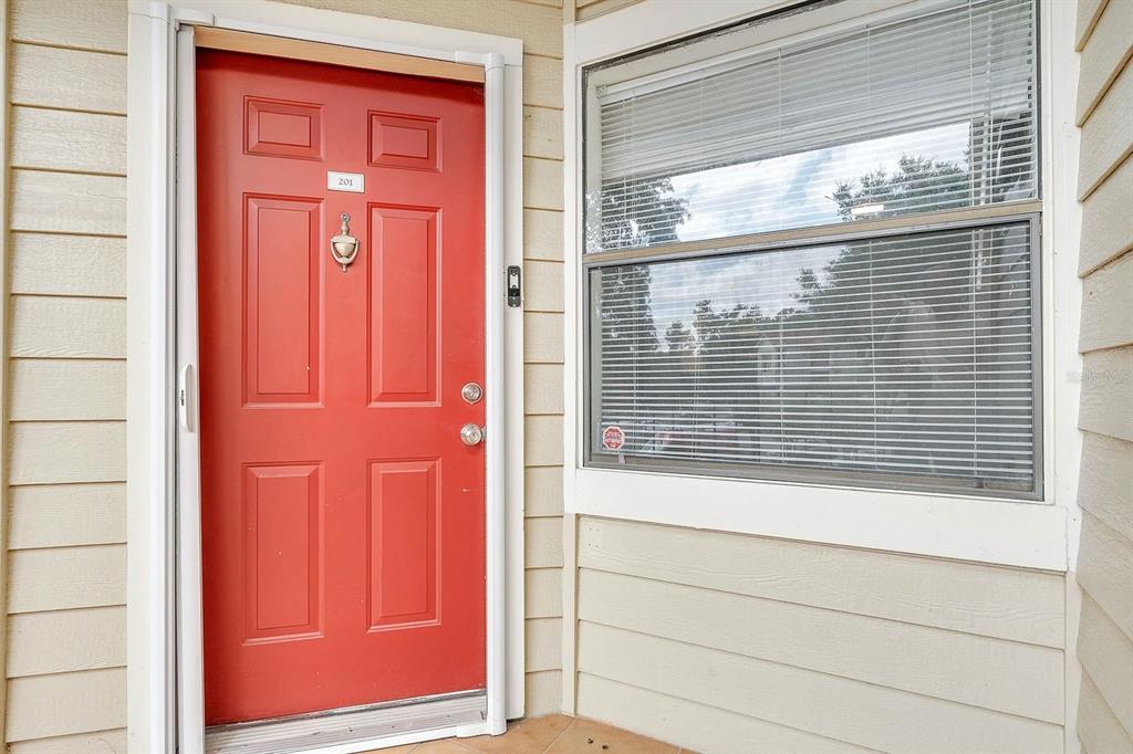 A red front door with a door knocker and a window with blinds — 3032 PARKWAY BOULEVARD UNIT 201, KISSIMMEE, FL