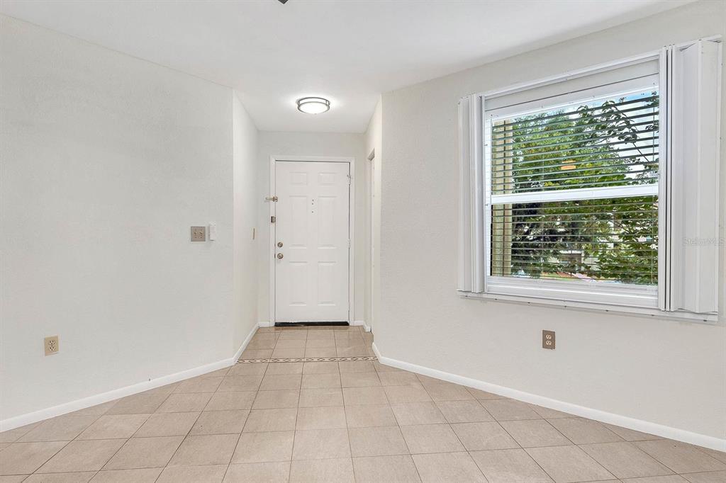 An entryway with beige tile flooring, a white front door, and a window with blinds — 3032 PARKWAY BOULEVARD UNIT 201, KISSIMMEE, FL