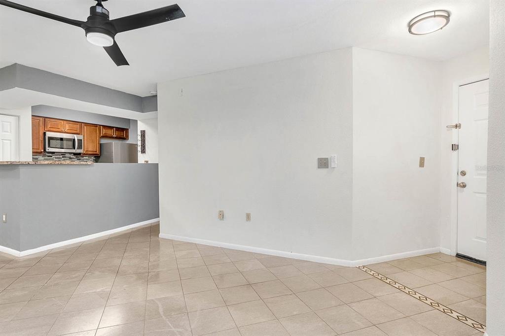 An open-concept living area features tiled floors, a ceiling fan, and a kitchen pass-through — 3032 PARKWAY BOULEVARD UNIT 201, KISSIMMEE, FL