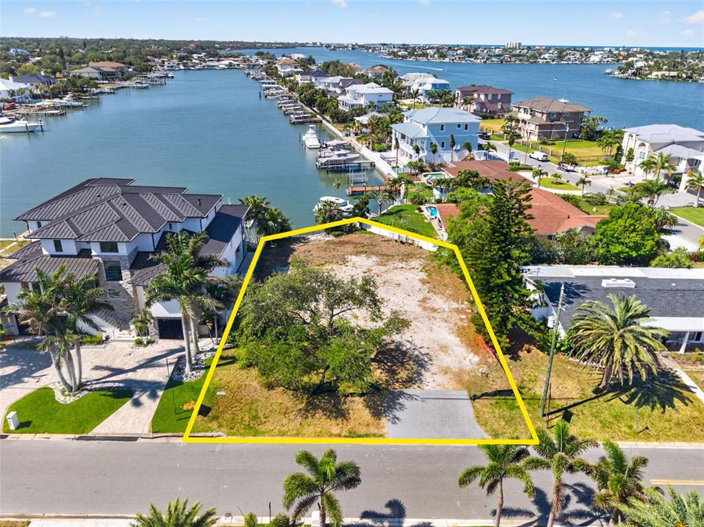 An aerial view shows a vacant waterfront lot outlined in yellow near a residential street — 909 OAKWOOD DRIVE, LARGO, FL
