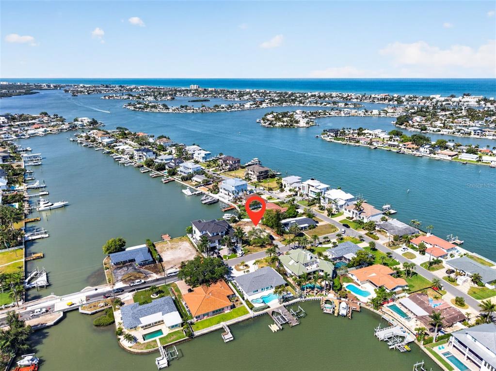 An aerial view shows a vacant waterfront lot marked with a red pin — 909 OAKWOOD DRIVE, LARGO, FL