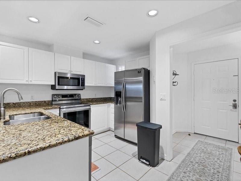 A kitchen with white cabinets, granite countertops, stainless steel appliances, and tile flooring — 3706 54TH DRIVE W UNIT 103, BRADENTON, FL