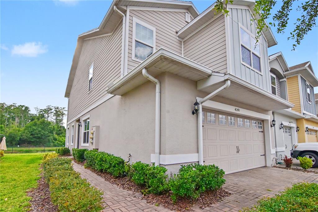 A two-story house with beige siding, a stucco lower level, and a paved driveway — 4240 GUMBO LIMBO DRIVE, ORLANDO, FL