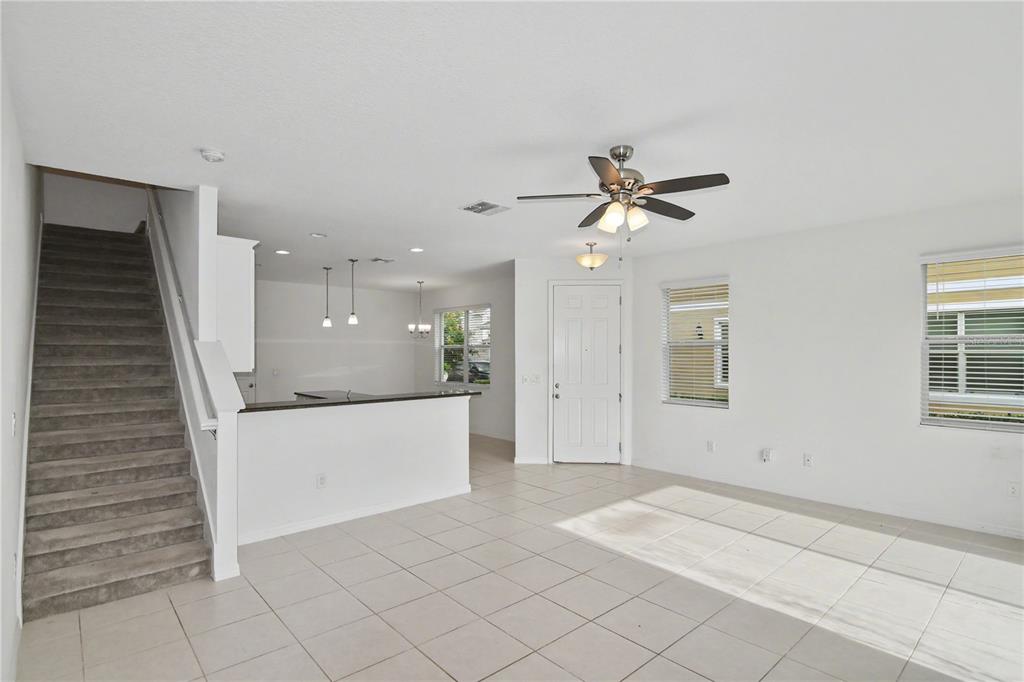 An open-concept living area features a carpeted staircase, tile flooring, and a kitchen breakfast bar — 4240 GUMBO LIMBO DRIVE, ORLANDO, FL