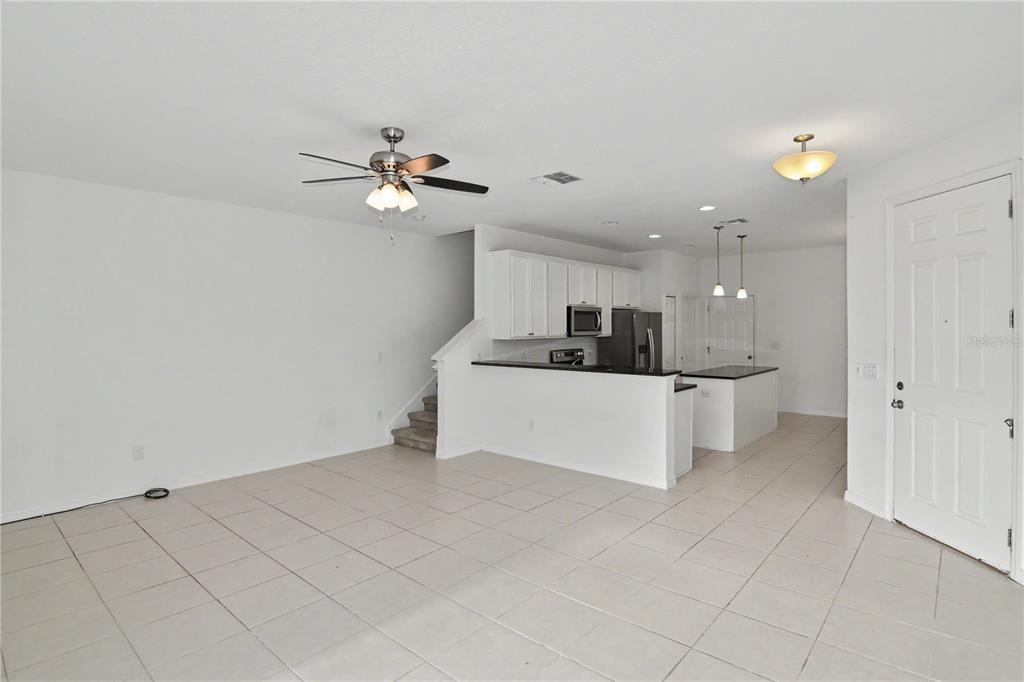 An open-concept living area with tile flooring, a kitchen with white cabinets, and a staircase — 4240 GUMBO LIMBO DRIVE, ORLANDO, FL