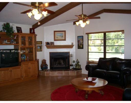 A living room features a fireplace, wood cabinetry, ceiling fans, and a leather sofa — 11520 NW 26th St, Plantation FL 33323, PLANTATION, FL