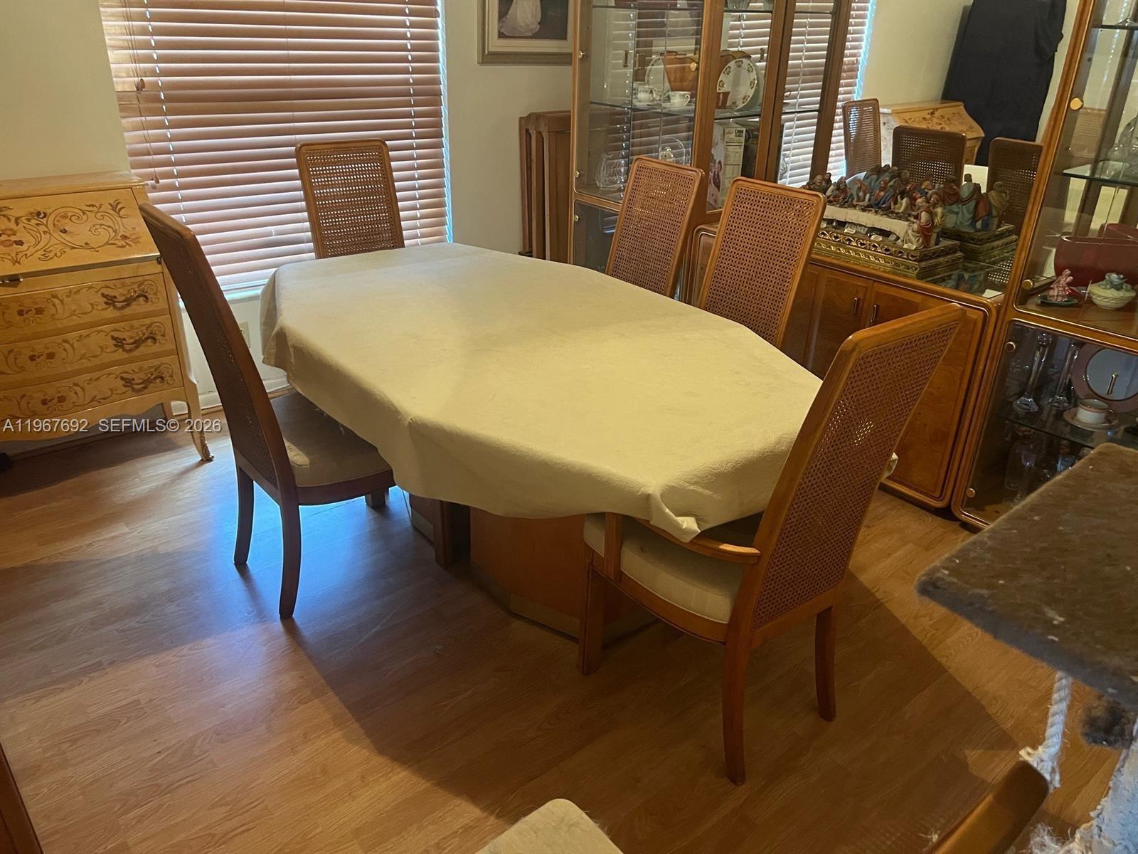 A dining room features a table with a beige tablecloth and six cane-back chairs — 11520 NW 26th St, Plantation FL 33323, PLANTATION, FL