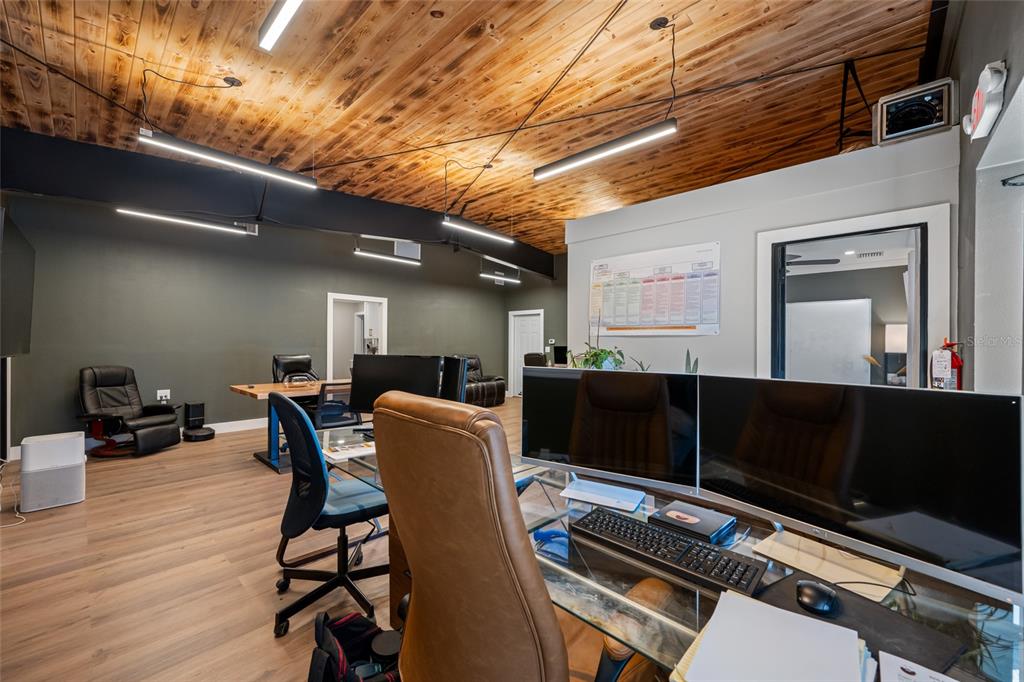 An office space features a wood-paneled ceiling, dark walls, and multiple desks with computer monitors — 620 UNION STREET, DUNEDIN, FL