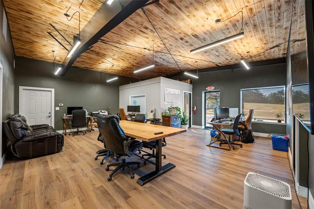 A modern office space features a wood-paneled ceiling, dark walls, and a large central desk — 620 UNION STREET, DUNEDIN, FL