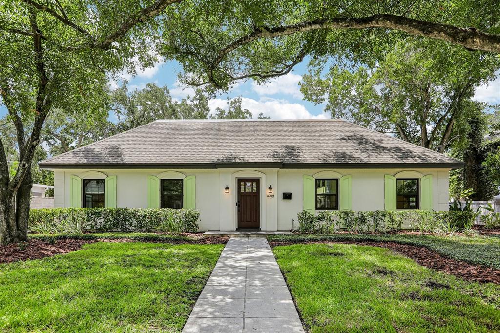 A single-story white house with light green shutters and a front walkway under large trees — 4708 W NEPTUNE STREET, TAMPA, FL