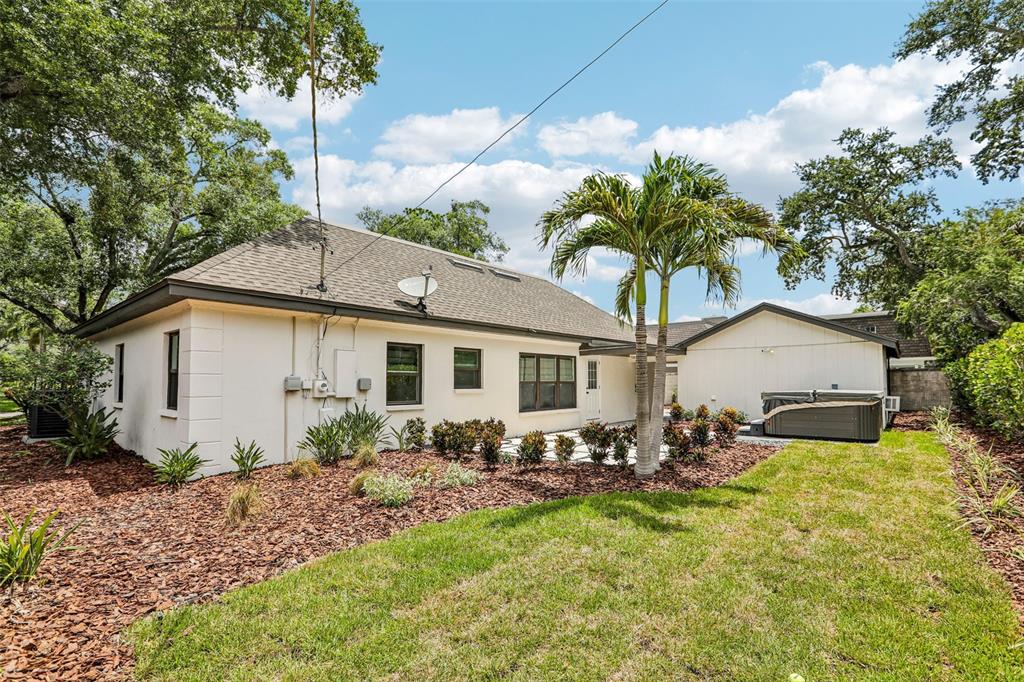 The exterior of a single-story house features a backyard with a hot tub and palm tree — 4708 W NEPTUNE STREET, TAMPA, FL