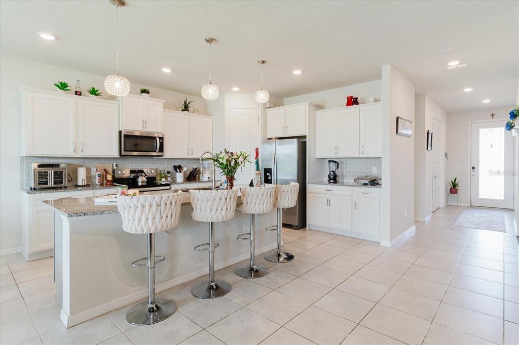 A kitchen with white cabinets, granite countertops, a breakfast bar with stools, and tile flooring — 10307 WINE PRESS AVENUE, RIVERVIEW, FL