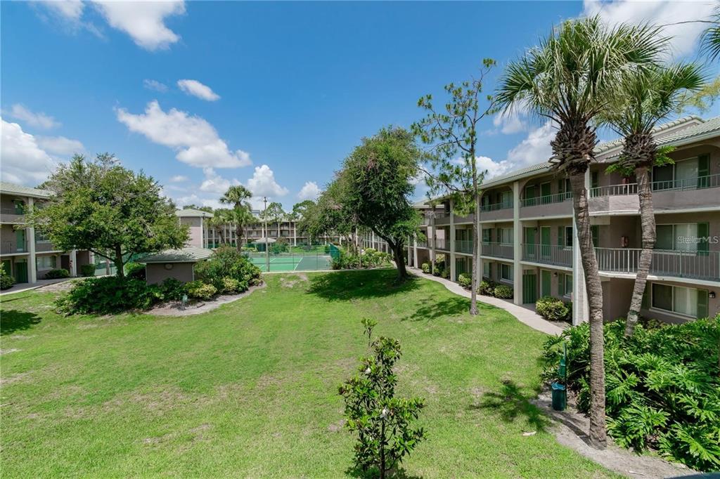 An exterior view of a multi-story apartment complex with a central lawn and tennis court — 139 OYSTER BAY CIRCLE UNIT 200, ALTAMONTE SPRINGS, FL