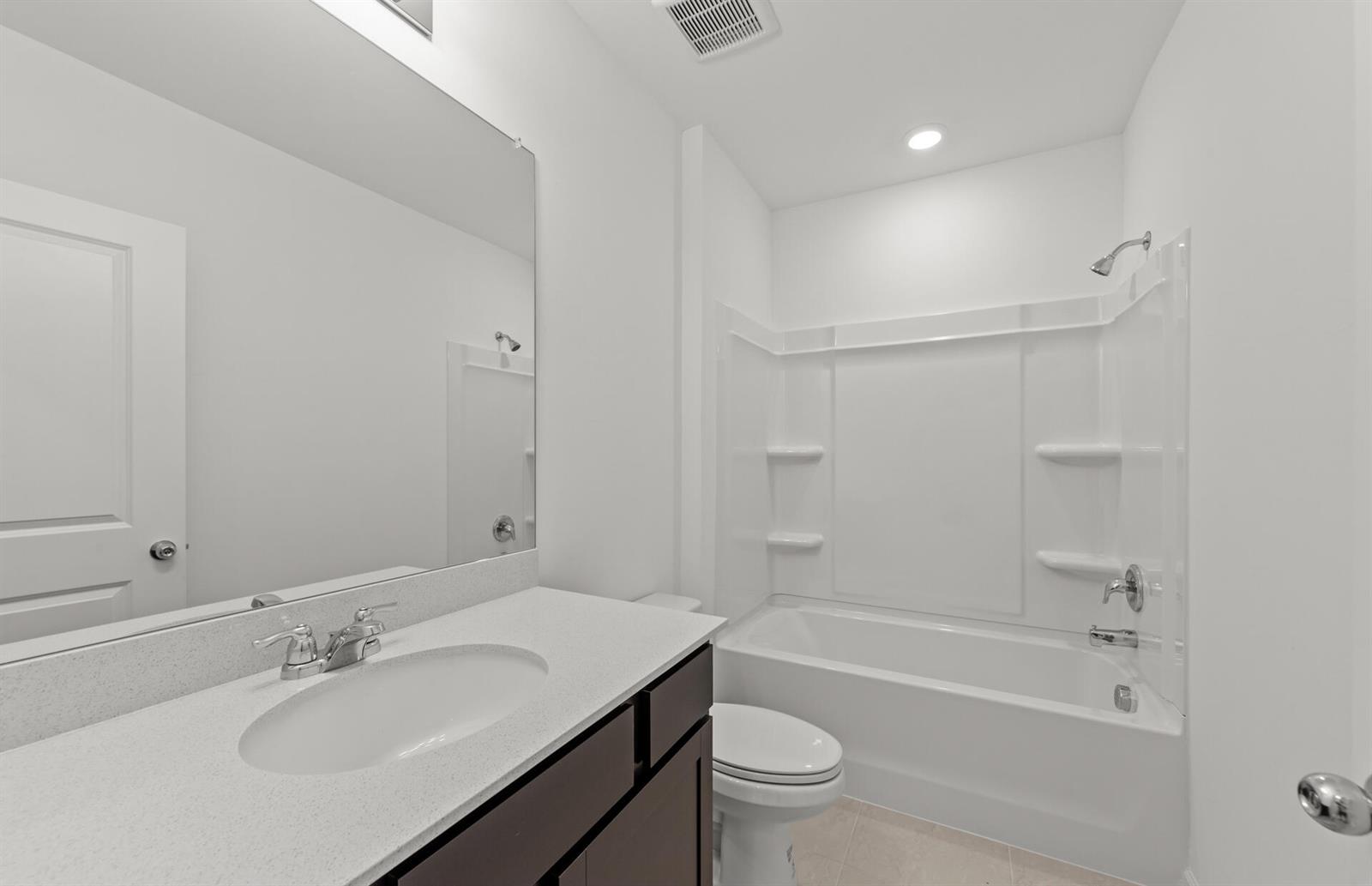 A bathroom features a dark wood vanity, a white countertop, and a tub-shower combination — 1025 Caloosa Breeze Drive, FL 33935, FL