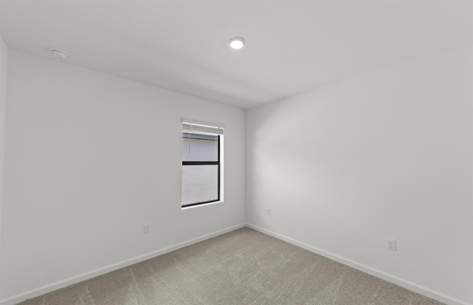 An empty bedroom features white walls, gray carpet, a single window, and a ceiling light — 1025 Caloosa Breeze Drive, FL 33935, FL
