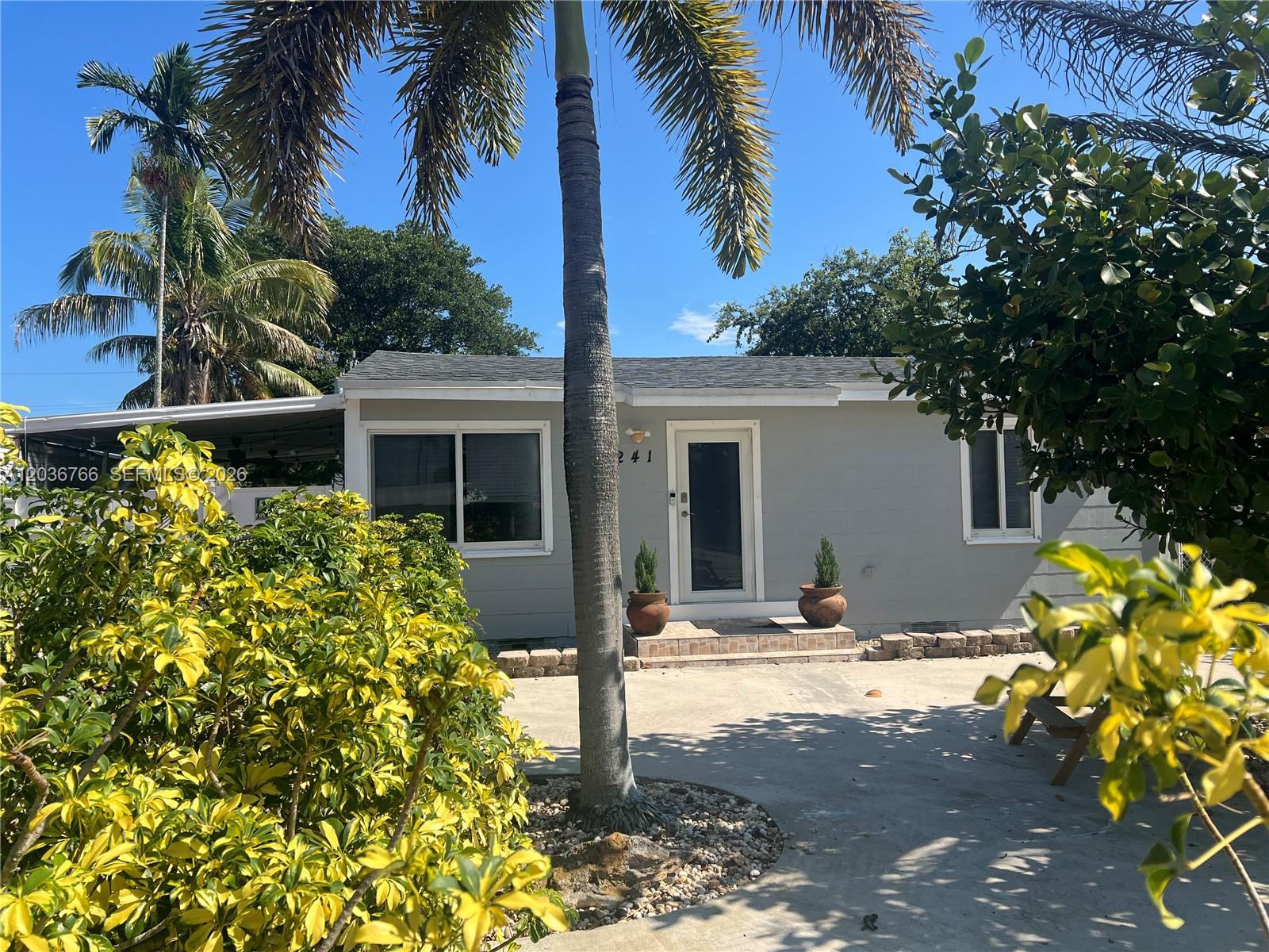 A single-story gray house features a palm tree in the front yard and a driveway — 241 SW 3rd Ter # 0, Dania Beach FL 33004, DANIA BEACH, FL