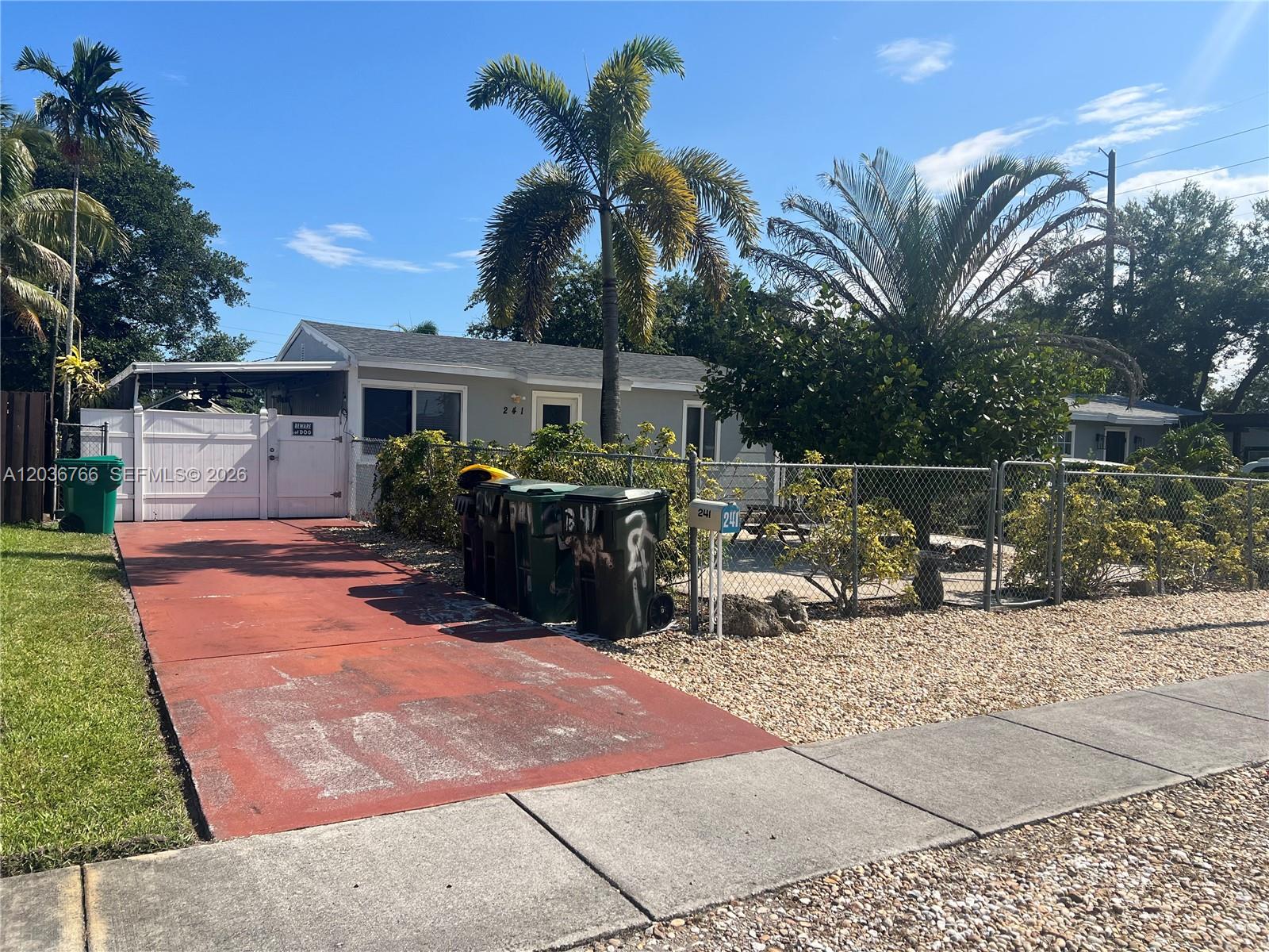 A single-story house with a red driveway, palm trees, and a chain-link fence — 241 SW 3rd Ter # 0, Dania Beach FL 33004, DANIA BEACH, FL
