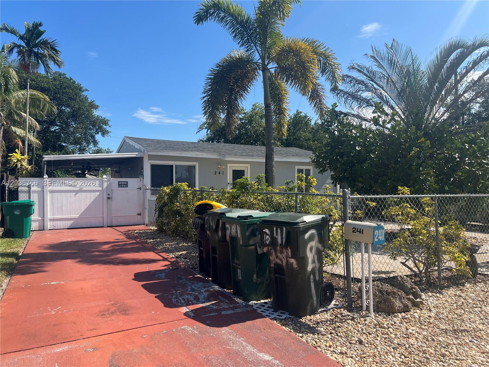 A single-story house with a red driveway, several trash bins, and palm trees — 241 SW 3rd Ter # 0, Dania Beach FL 33004, DANIA BEACH, FL