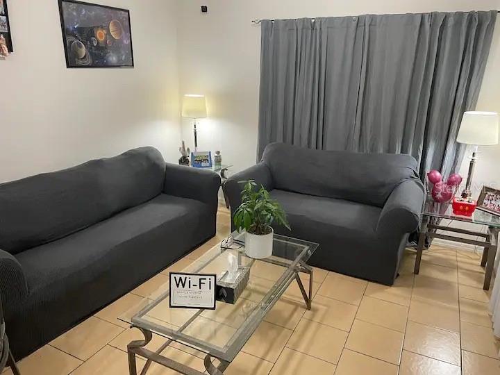 A living room features two dark gray sofas, a glass coffee table, and tile flooring — 2250 SAN VITAL DRIVE UNIT 107, KISSIMMEE, FL