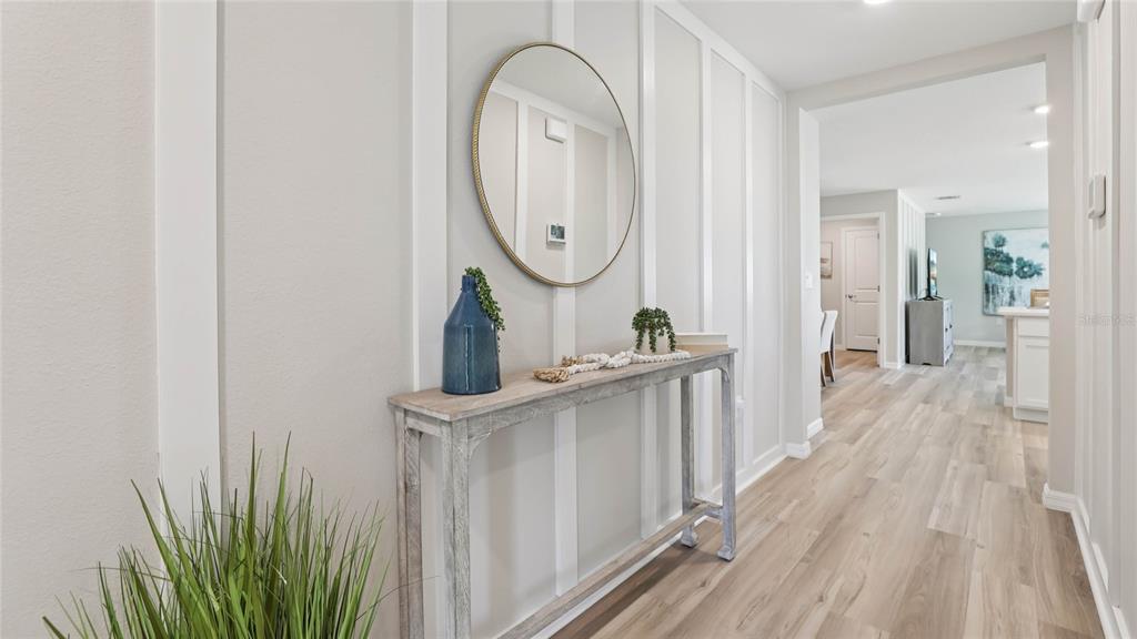 A hallway features light wood flooring, board and batten walls, and a console table — 11085 NW 167TH TERRACE, ALACHUA, FL