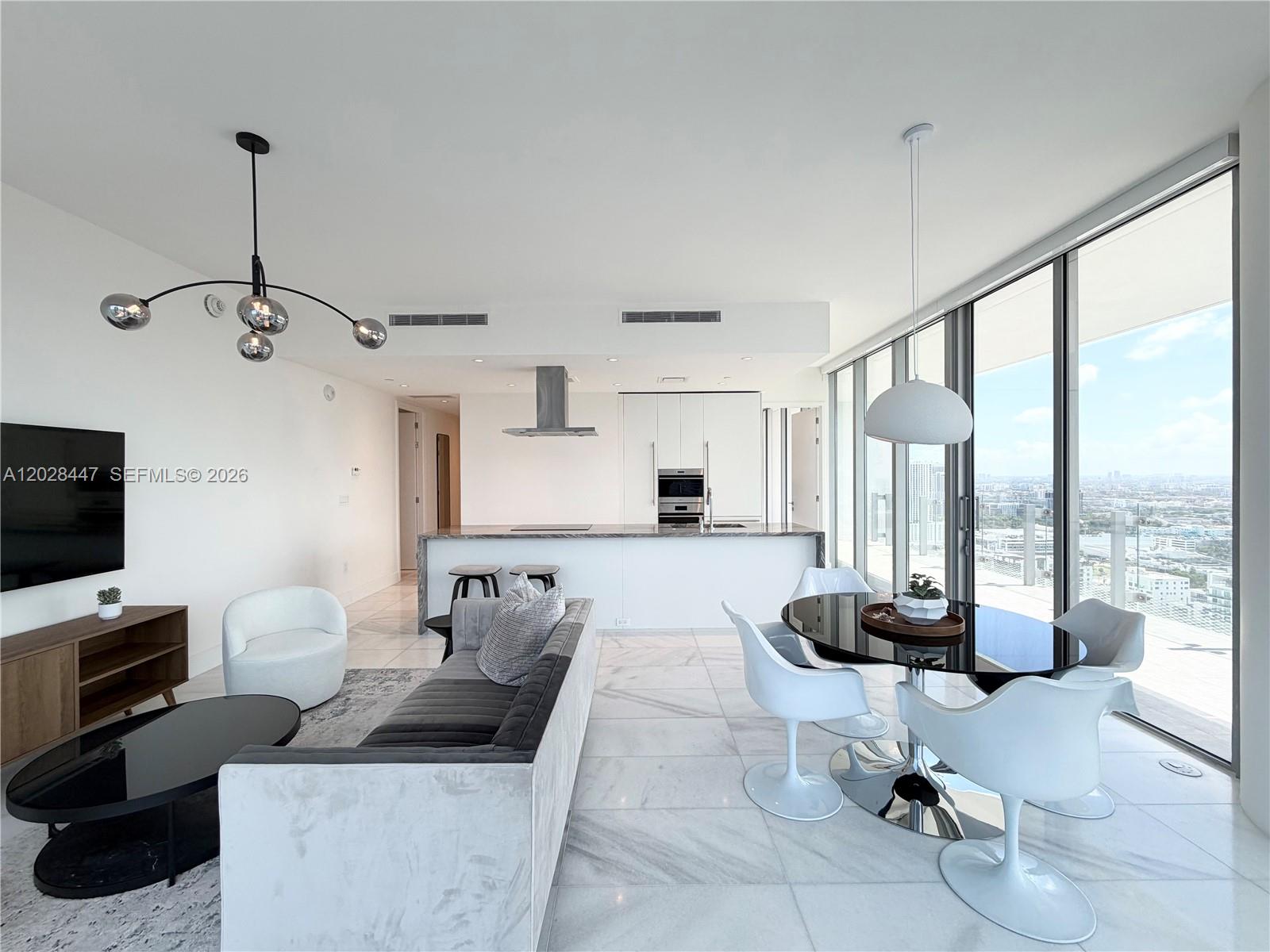 A modern open-concept living and dining area features white marble floors and floor-to-ceiling windows — 700 NE 26th Ter # 3206, Miami FL 33137, MIAMI, FL