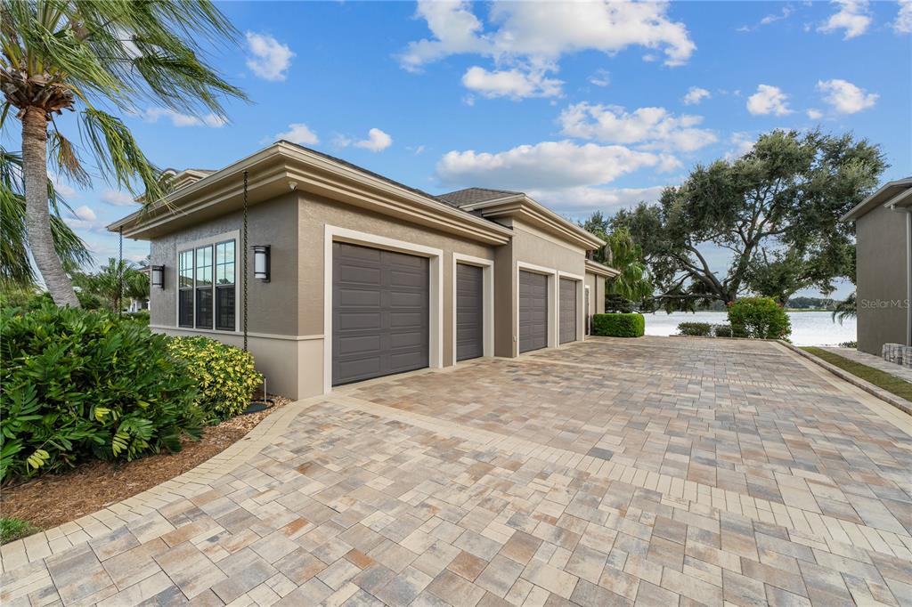 A tan house exterior features a multi-car garage and a paved driveway near a lake — 414 MEANDERING WAY, POLK CITY, FL