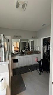A bathroom features a double vanity with white cabinets, a large mirror, and a shower — 1701 BULL HILL ROAD, KISSIMMEE, FL