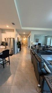 A view from a kitchen looking toward a living room with tile flooring throughout — 1701 BULL HILL ROAD, KISSIMMEE, FL