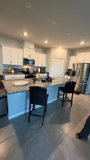 A kitchen features white cabinets, granite countertops, a center island with bar stools, and stainless appliances — 1701 BULL HILL ROAD, KISSIMMEE, FL
