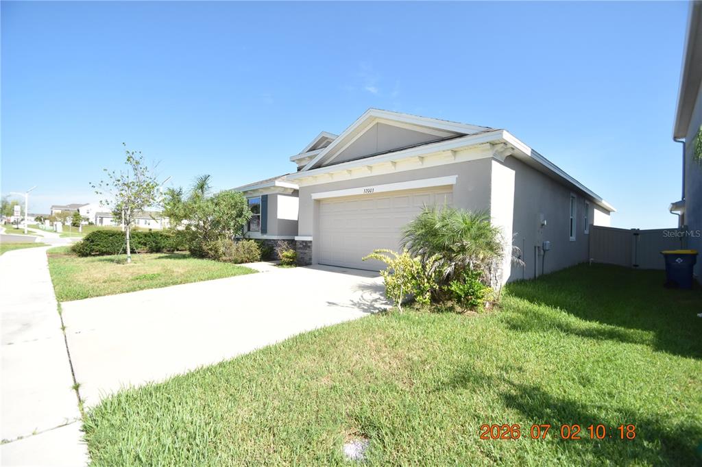 A single-story house with a beige exterior, a two-car garage, and a concrete driveway — 32003 CONCHSHELL SAIL STREET, WESLEY CHAPEL, FL