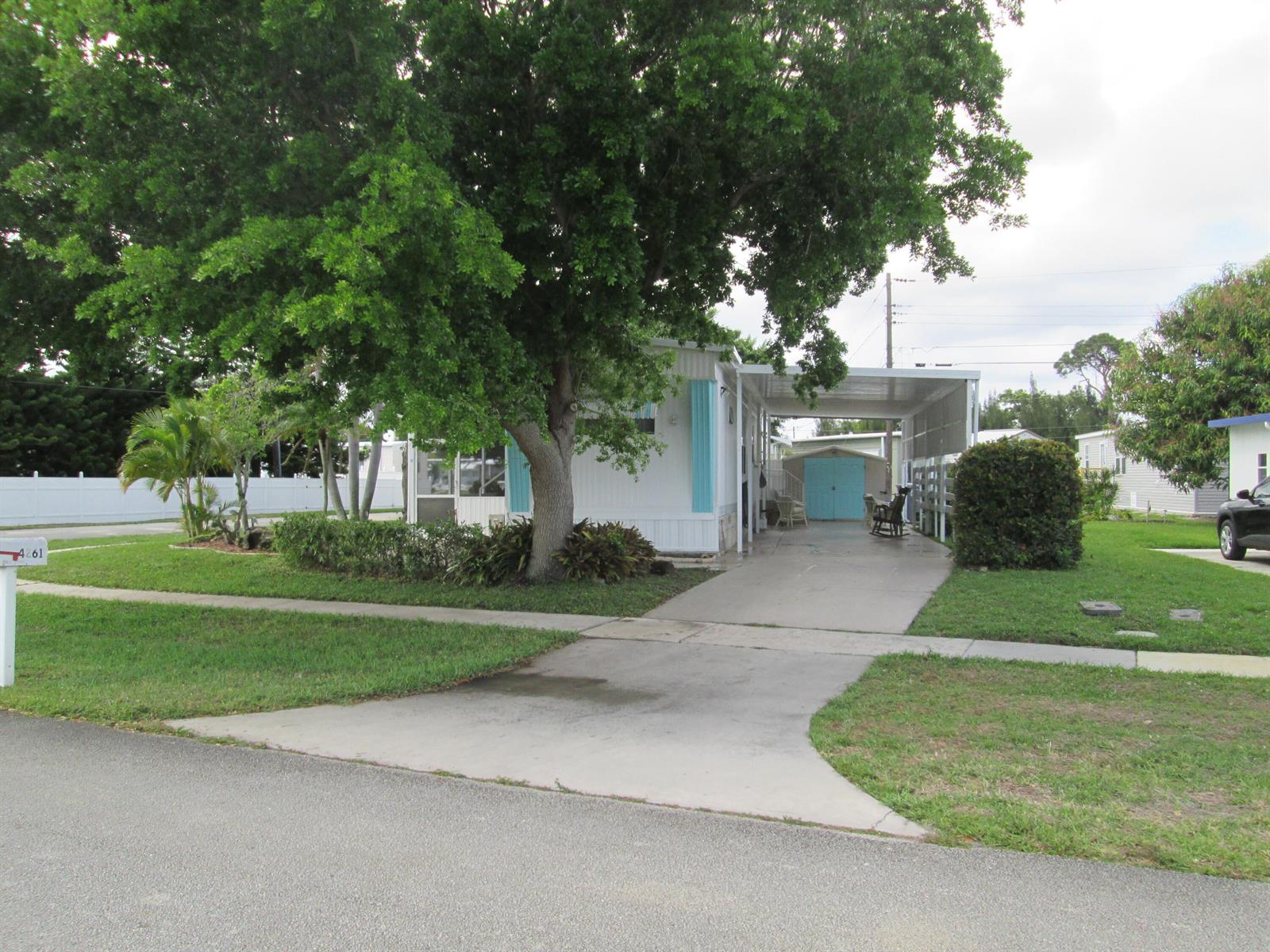 A single-story mobile home features a large tree, a carport, and a concrete driveway — 4261 Meadow View Drive, Boynton Beach FL 33436, BOYNTON BEACH, FL