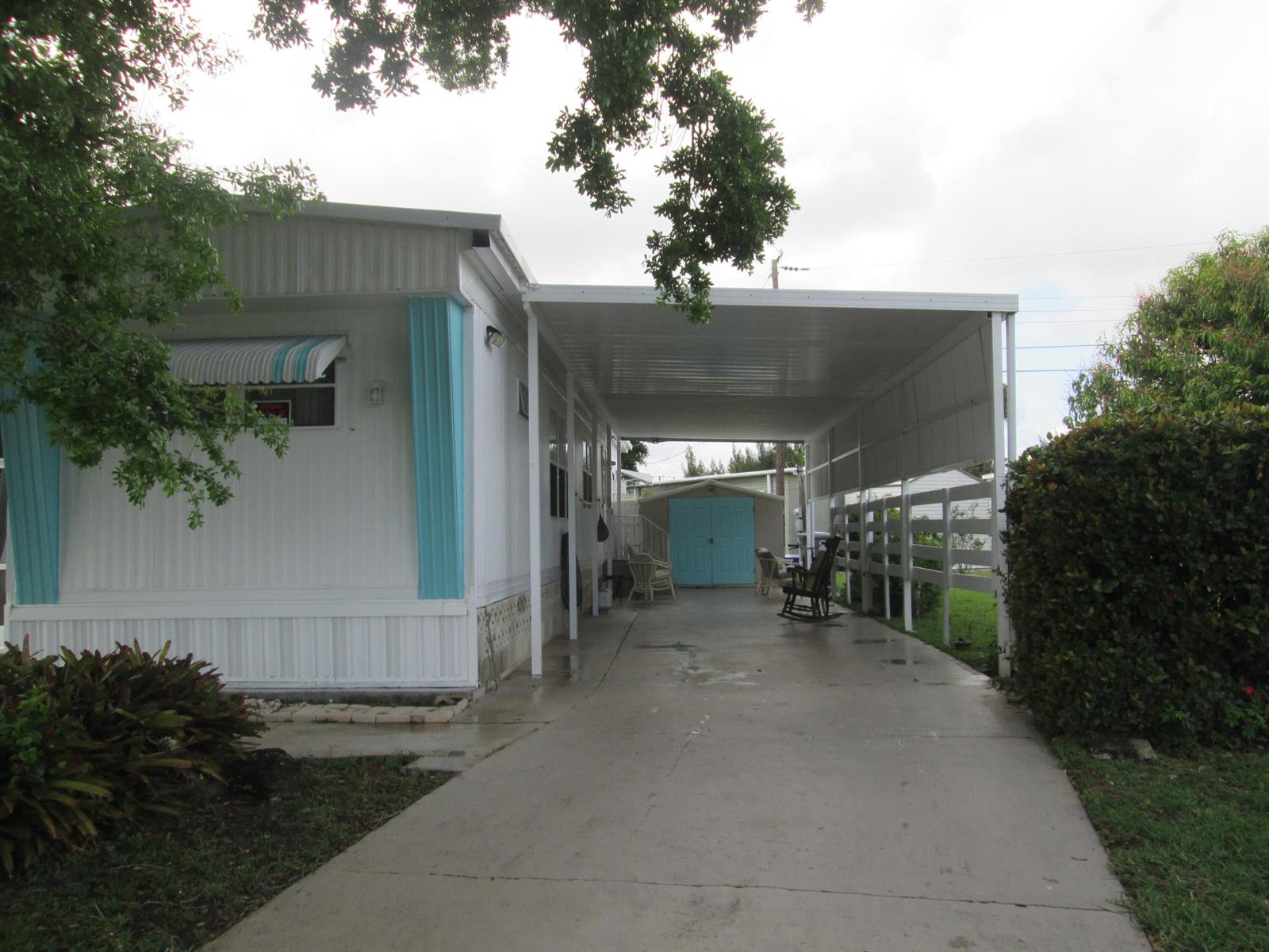 A white mobile home features a large carport, a blue shed, and a concrete driveway — 4261 Meadow View Drive, Boynton Beach FL 33436, BOYNTON BEACH, FL