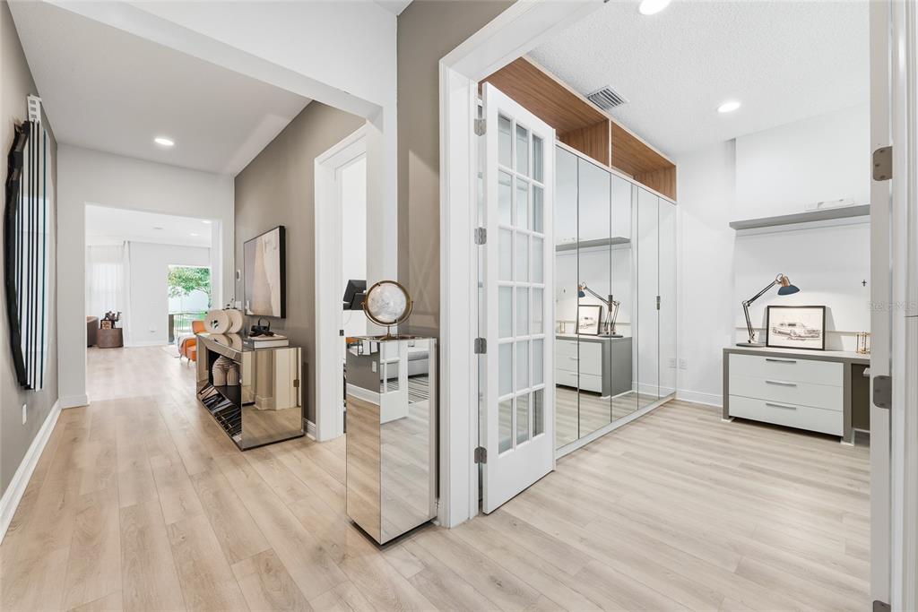 A hallway leads to a room with mirrored closet doors, a desk, and light wood flooring — 15790 SWEET LIMETTA DRIVE, WINTER GARDEN, FL