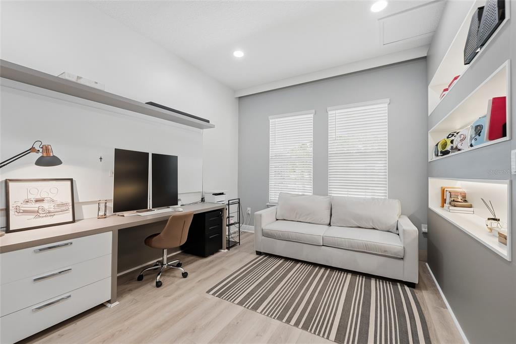 A home office features a built-in desk, a sofa, and recessed shelving against a gray wall — 15790 SWEET LIMETTA DRIVE, WINTER GARDEN, FL