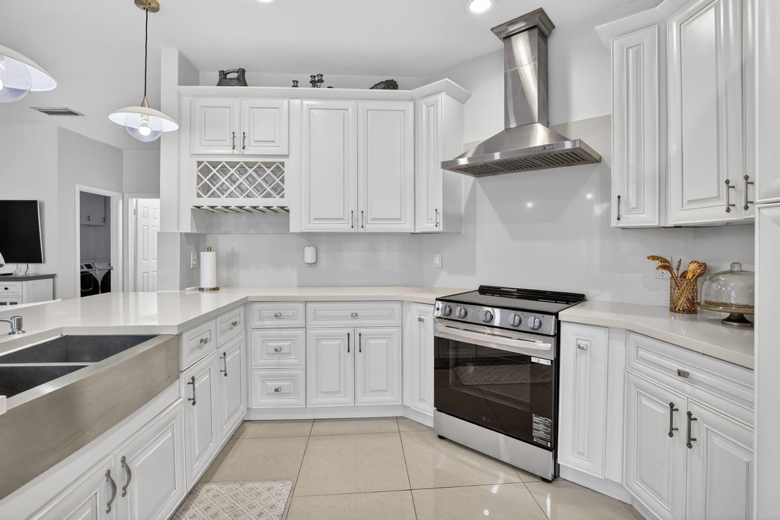 A white kitchen features stainless steel appliances, a farmhouse sink, and light-colored countertops — 711 Heritage Way, Weston FL 33326, WESTON, FL