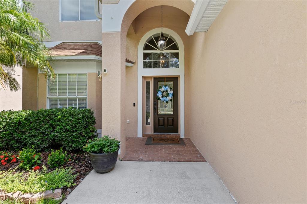 The exterior entrance features a brown front door with a wreath under an arched portico — 18923 FISHERMANS BEND DRIVE, LUTZ, FL