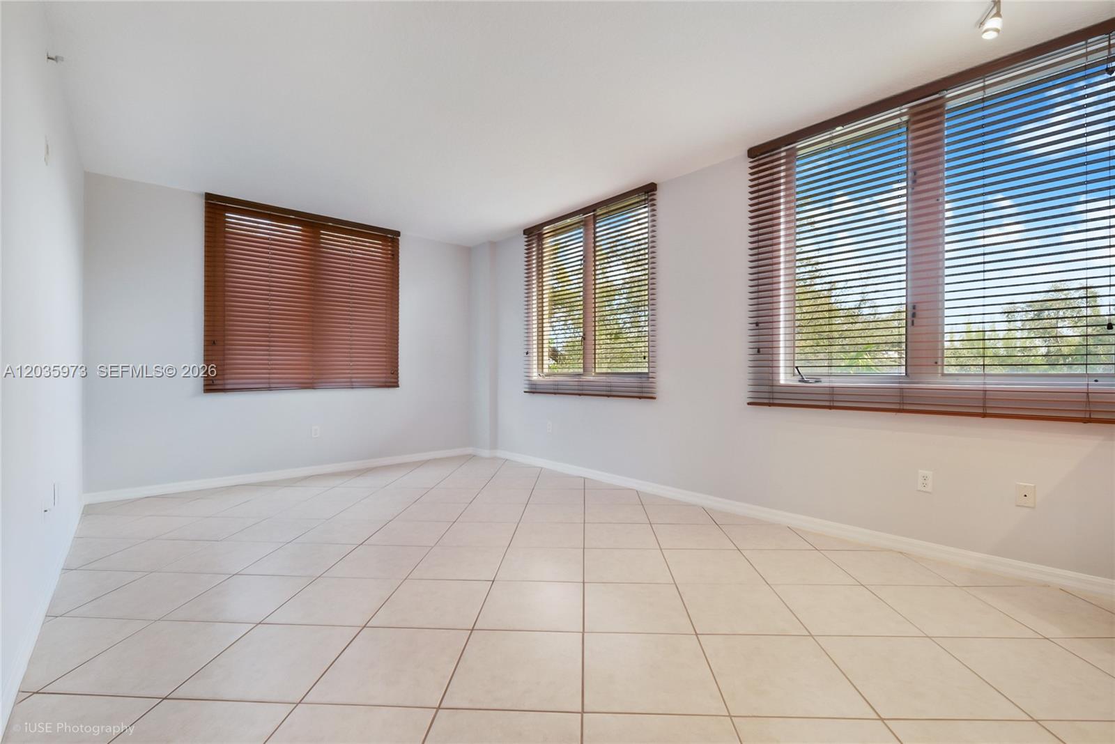 An empty room features light-colored tile flooring, white walls, and windows with brown blinds — 2630 SW 28th St # 53, Miami FL 33133, MIAMI, FL