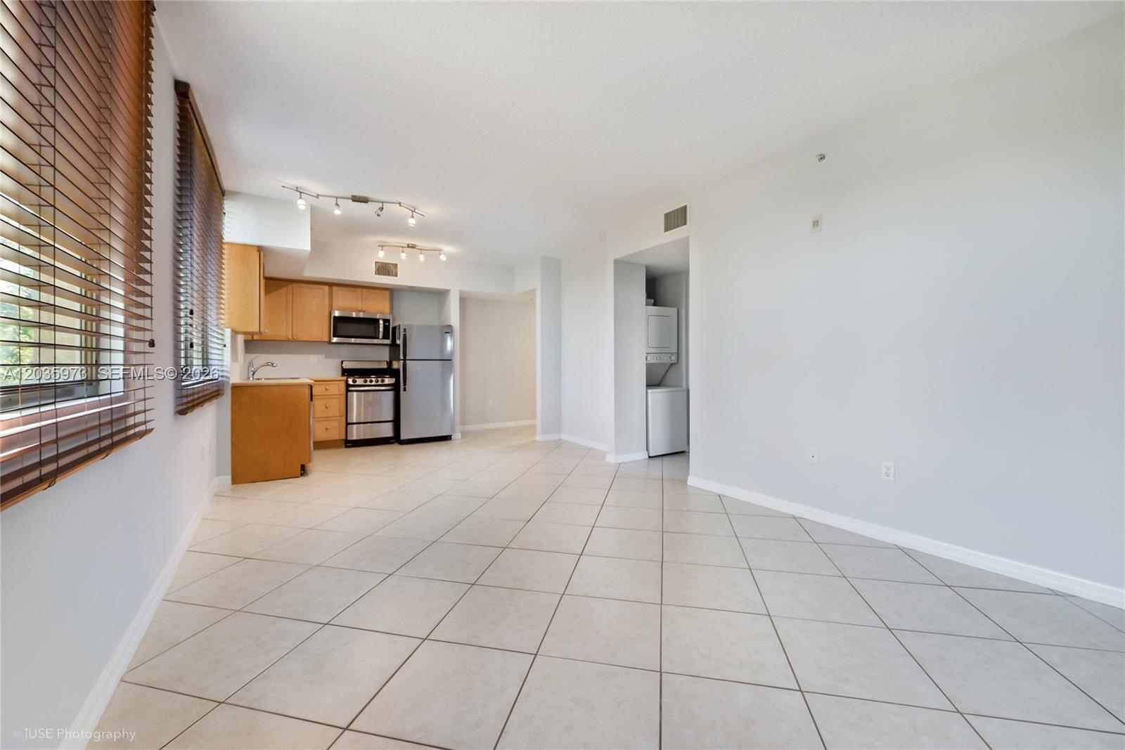 An open-concept kitchen and living area features light-colored tile flooring and wooden cabinetry — 2630 SW 28th St # 53, Miami FL 33133, MIAMI, FL