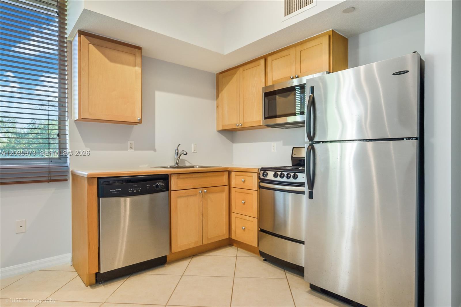 A kitchen features light wood cabinets, stainless steel appliances, and beige tile flooring — 2630 SW 28th St # 53, Miami FL 33133, MIAMI, FL